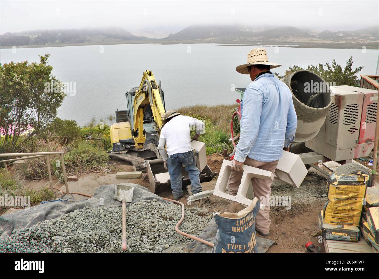 Mexikanische Arbeiter bauen eine Zementmauer mit Blick auf Morro Bay Mündung in Zentral-Kalifornien Stockfoto