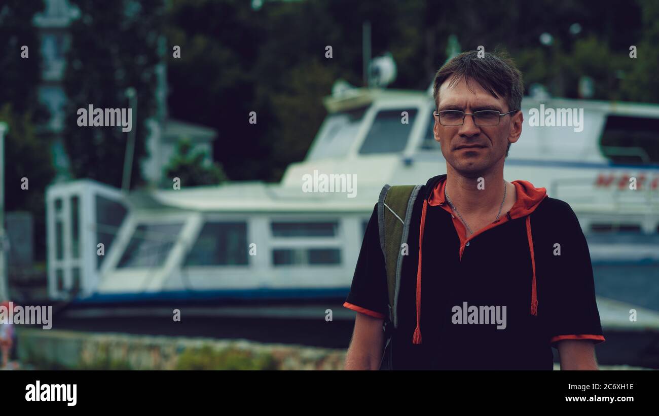 Reifer Mann mit Brille, die auf dem Damm steht. Erwachsene Männer genießen Spaziergang durch die Stadt. Stockfoto