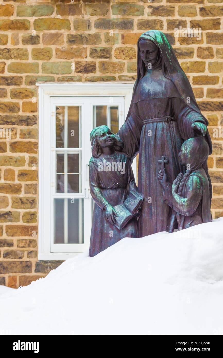 Bronzestatue einer Nonne mit einem indigenen Mädchen und einem kaukasischen Mädchen, die teilweise im tiefen Schnee in Quebec City Canada begraben sind Stockfoto