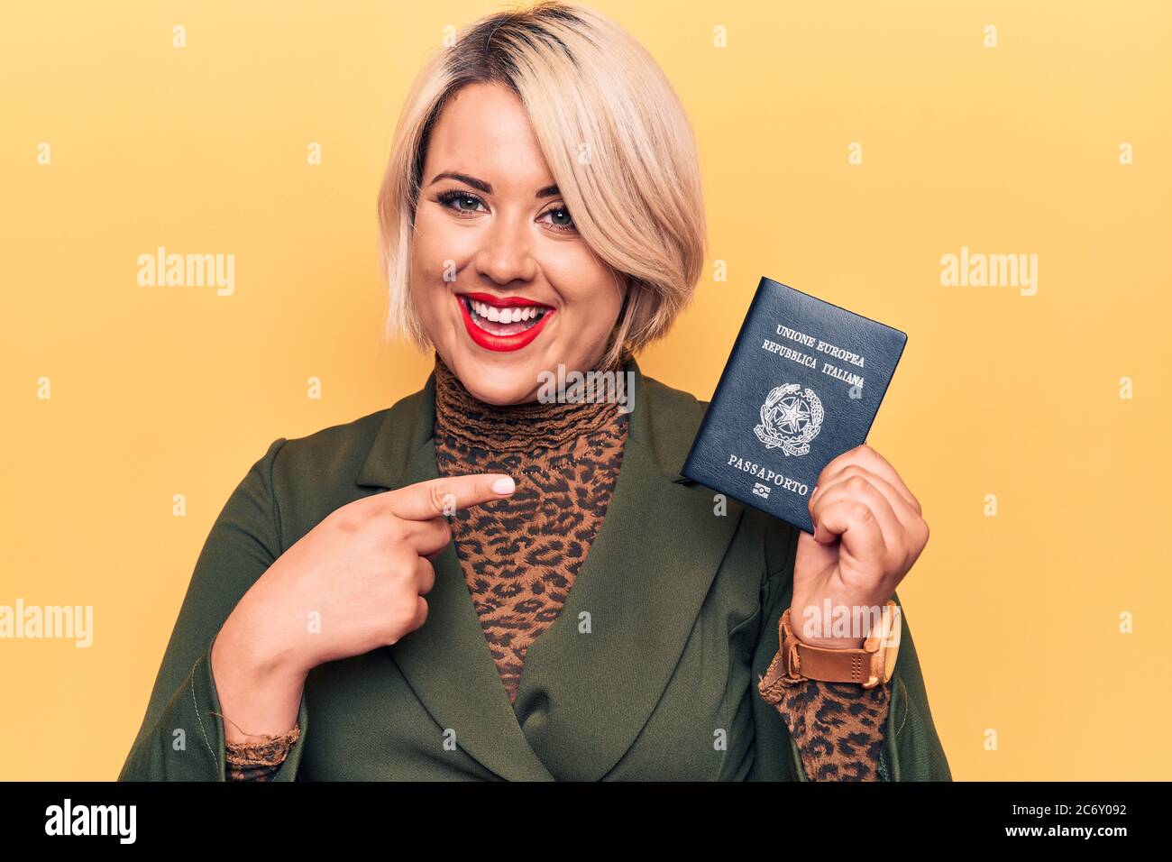Junge schöne plus size Tourist Frau hält Italien Itaian Pass über gelben Hintergrund lächelnd glücklich zeigt mit Hand und Finger Stockfoto