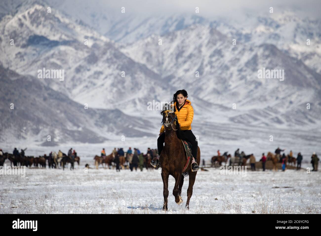 Eine ausländische Touristenin reitet ein einheimisches Pferd während eines Dorffiels Kok Boru im Gebiet Chuy in Kirgisistan in der Nähe der Hauptstadt Bischkek. Stockfoto