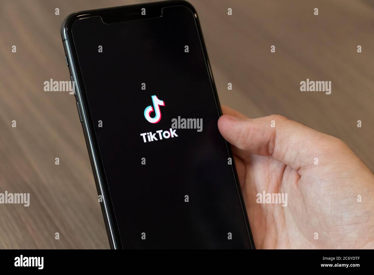 Person, die ein Telefon mit dem TikTok-Logo, der beliebten und umstrittenen chinesischen Video-Sharing-App auf dem Bildschirm. Stockfoto