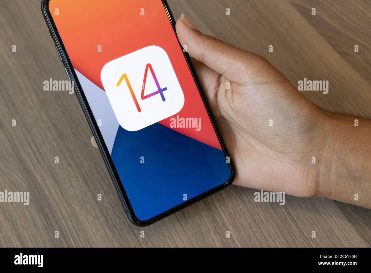 Person, die ein iPhone mit dem iOS 14 Logo auf ihm hält, Äpfel neueste Betriebssoftware. Stockfoto