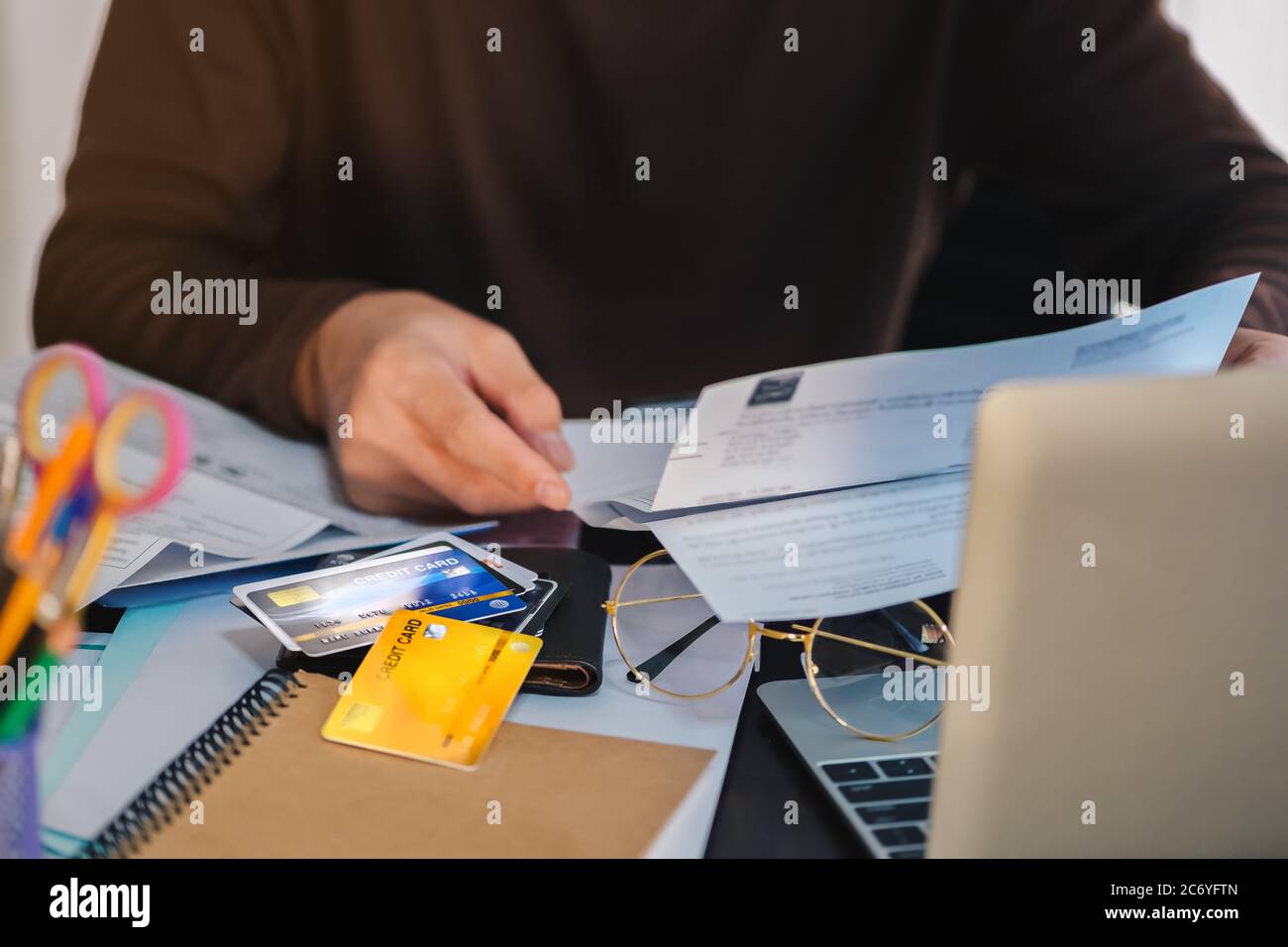 Mann Hand hält Rechnungen von vielen Kreditkarten während der Arbeit am Schreibtisch, konzentrieren sich auf Kreditkarte seichte DOF Stockfoto