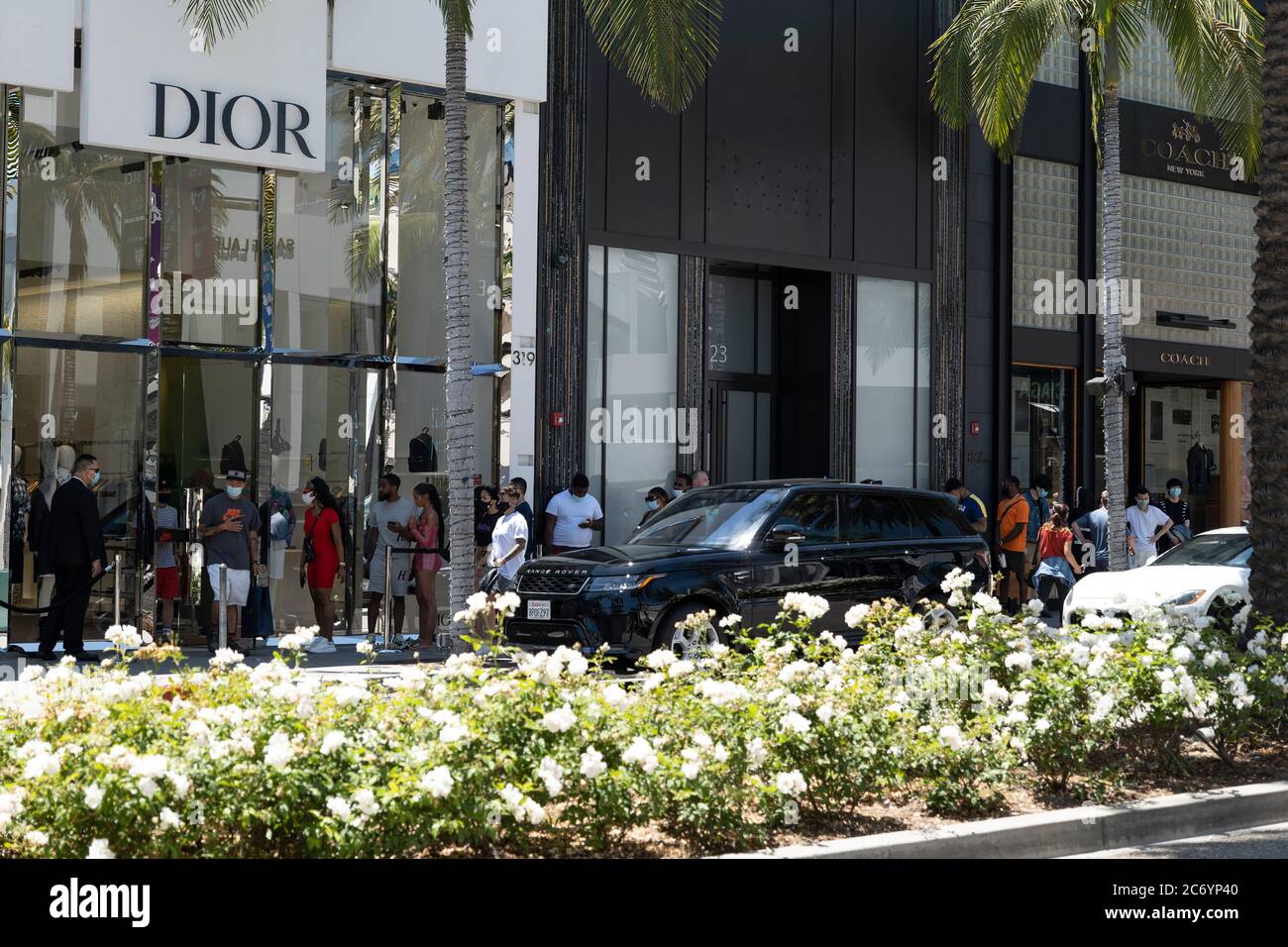 Beverly Hills, CA/USA - 12. Juli 2020: Eine Reihe von sozial distanzierenden Kunden in Gesichtsmasken warten vor dem Dior-Laden Rodeo Drive Stockfoto