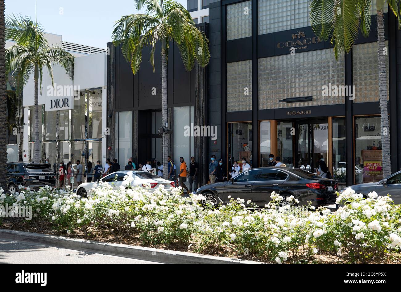 Beverly Hills, CA/USA - 12. Juli 2020: Eine Reihe von sozial distanzierenden Kunden in Gesichtsmasken warten vor Luxusgeschäften am Rodeo Drive Stockfoto