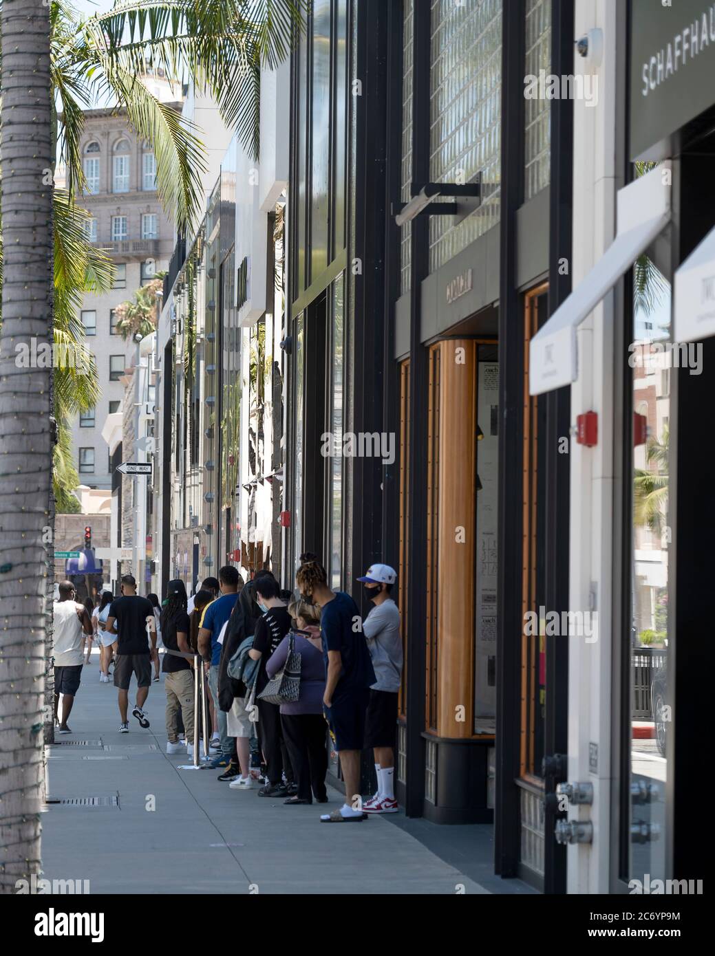 Beverly Hills, CA/USA - 12. Juli 2020: Eine Reihe von sozial distanzierenden Kunden in Gesichtsmasken warten vor den Geschäften am Rodeo Drive Stockfoto