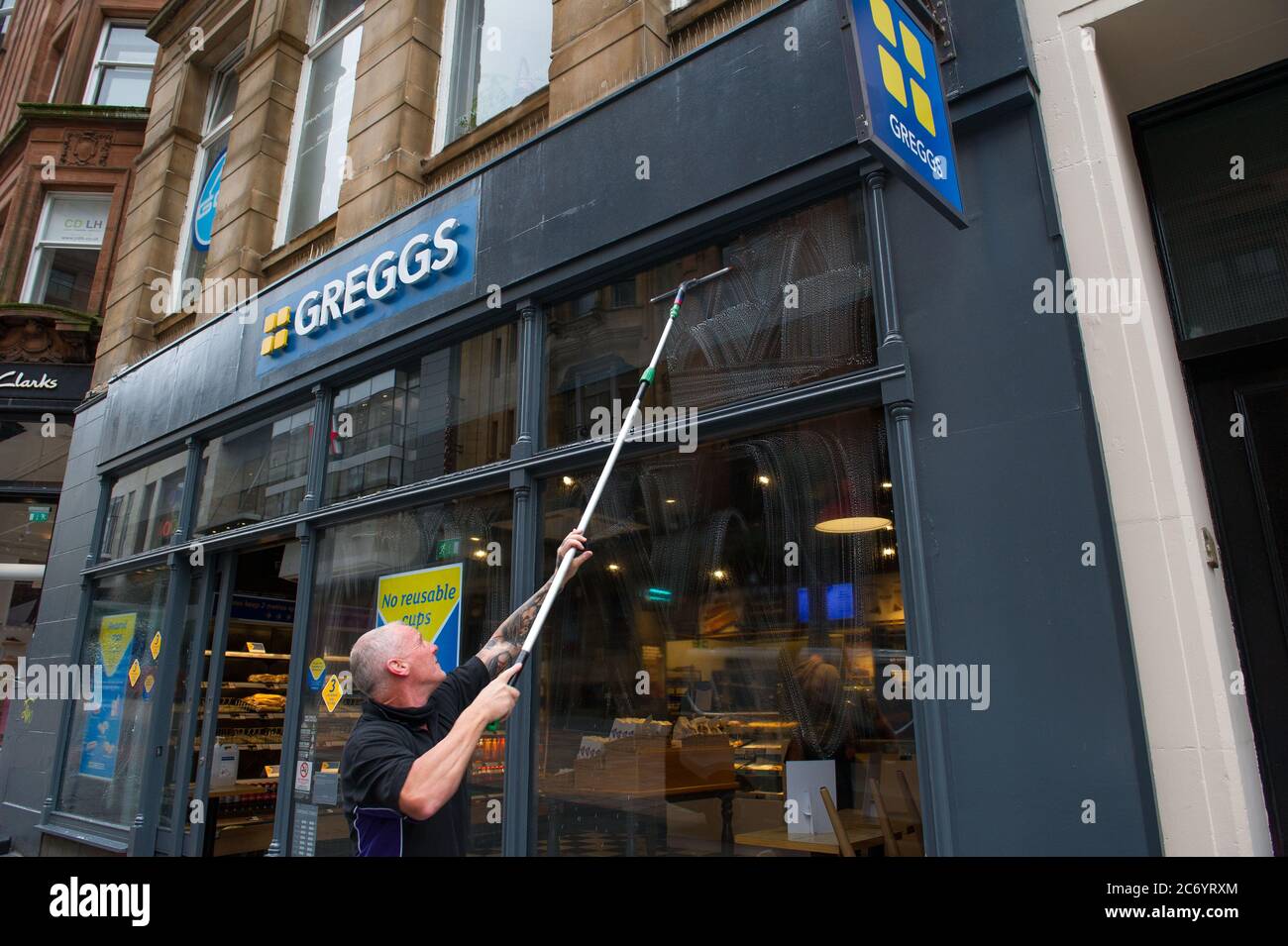Glasgow, Schottland, Großbritannien. Juli 2020. Im Bild: Ein Fensterputzer wäscht die Schaufenster von Gregs schnell, so dass sie am frühen Morgen funkeln. Szenen aus der Buchanan Street im Stadtzentrum von Glasgow. Quelle: Colin Fisher/Alamy Live News Stockfoto
