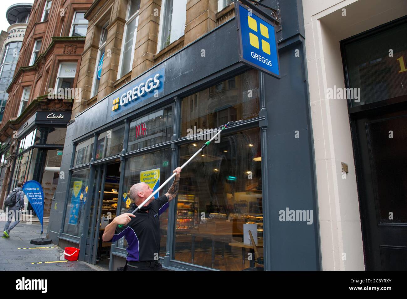 Glasgow, Schottland, Großbritannien. Juli 2020. Im Bild: Ein Fensterputzer wäscht die Schaufenster von Gregs schnell, so dass sie am frühen Morgen funkeln. Szenen aus der Buchanan Street im Stadtzentrum von Glasgow. Quelle: Colin Fisher/Alamy Live News Stockfoto