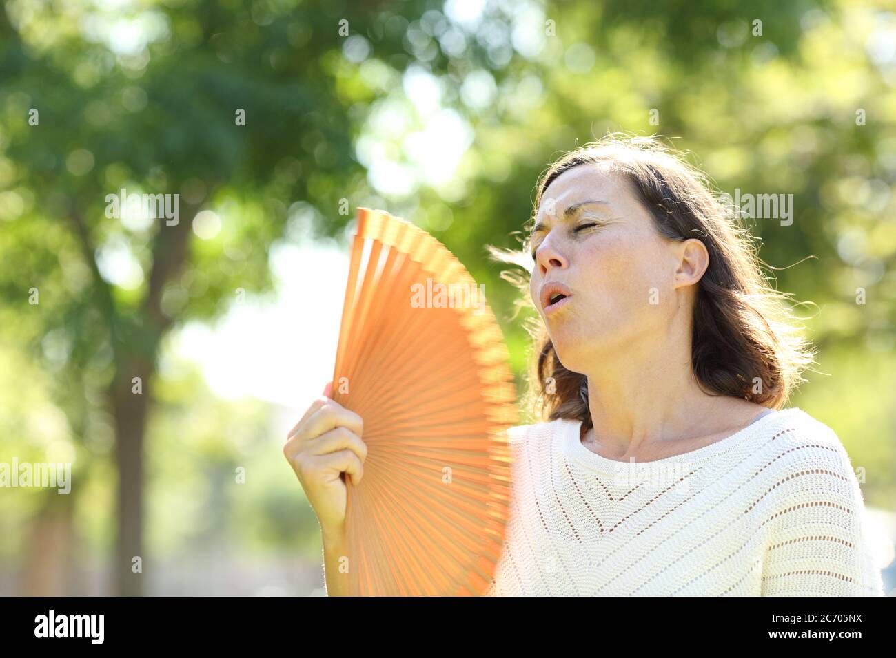 Erwachsene Frau mit Fan erfrischende leiden Hitzschlag im Park im Sommer stehen Stockfoto