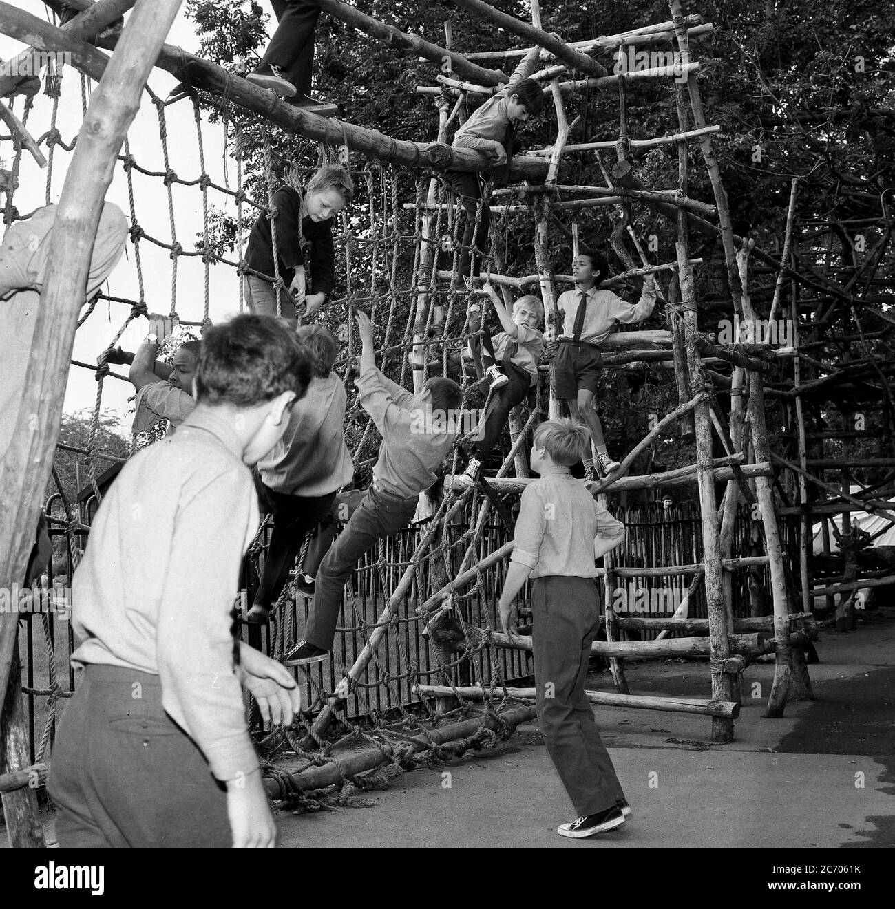 1960, historisch, draußen in einem Spielbereich, Schüler klettern Seilleitern auf einem handgefertigten Holzrahmen oder Struktur, in einem Außenbereich in einem inneren Londoner Jungen staatlichen Internat, Lewisham, South London, Stockfoto