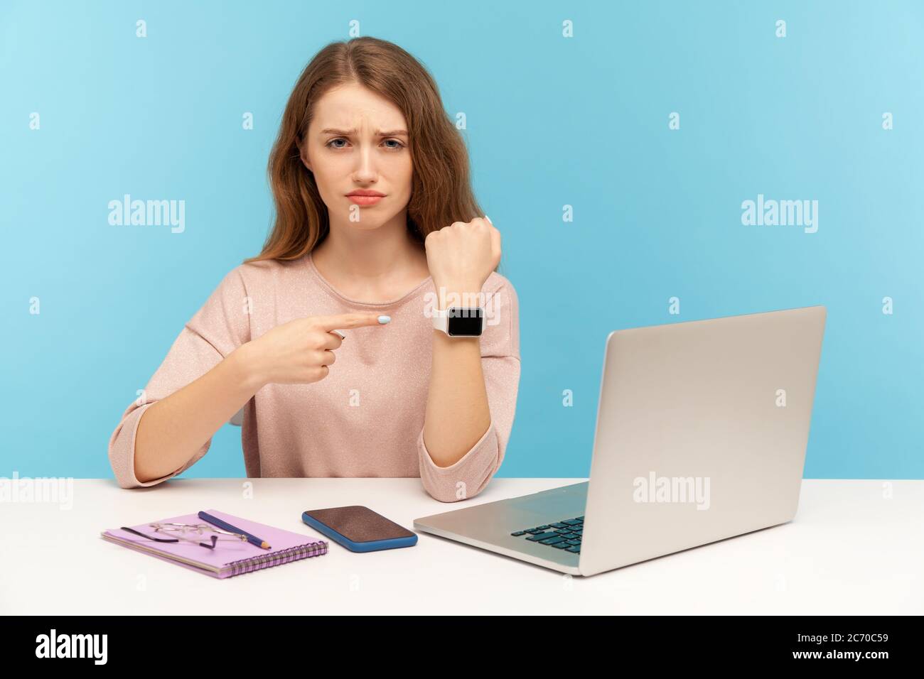 Verärgert müde Frau Angestellter sitzen im Büro und zeigt auf ihre Hand zu beobachten, düster verärgerten, erschöpft von Überstunden Arbeit und brauchen Pause. Stockfoto