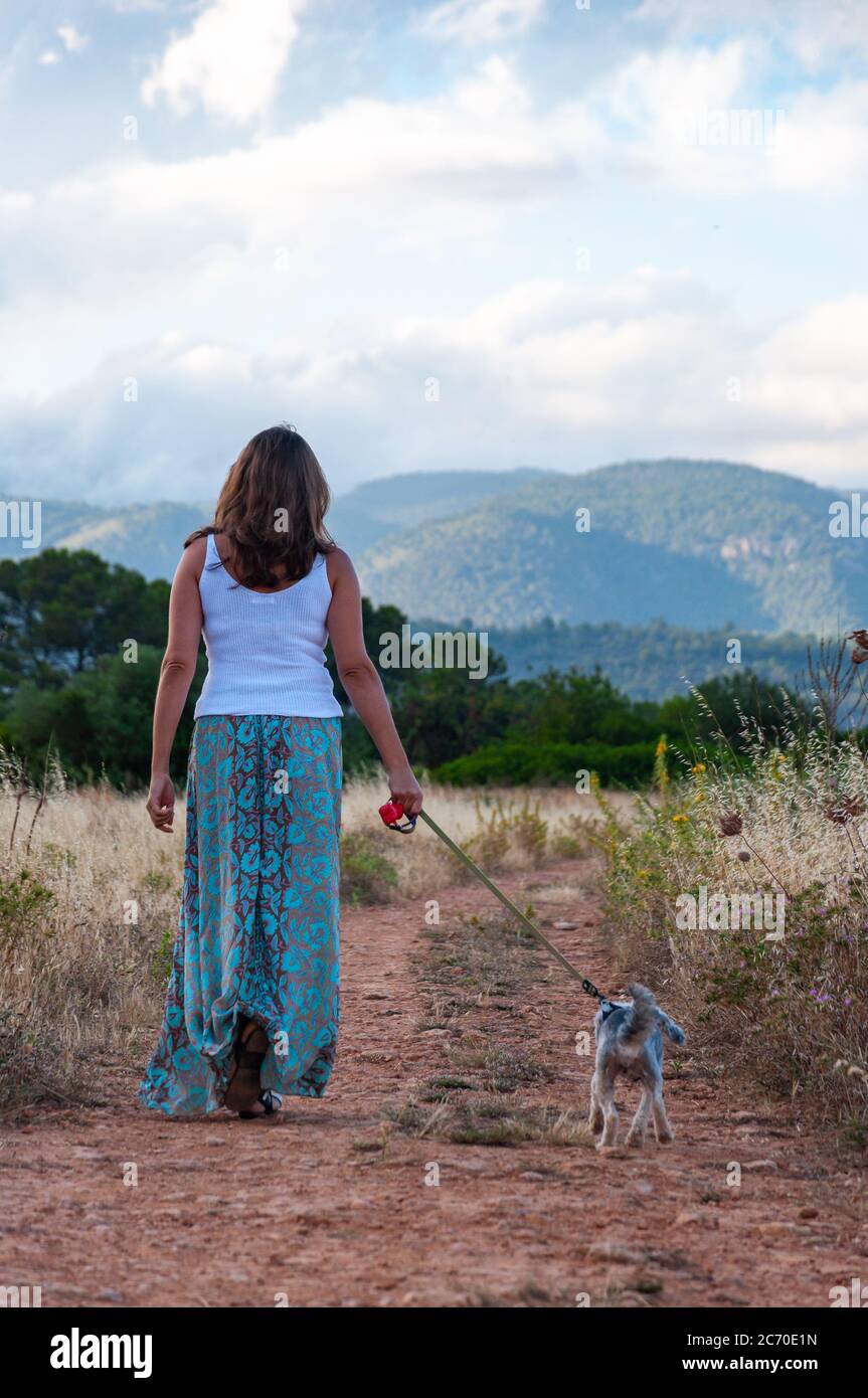 Frau, die allein mit ihrem Hund im Wald geht Stockfoto