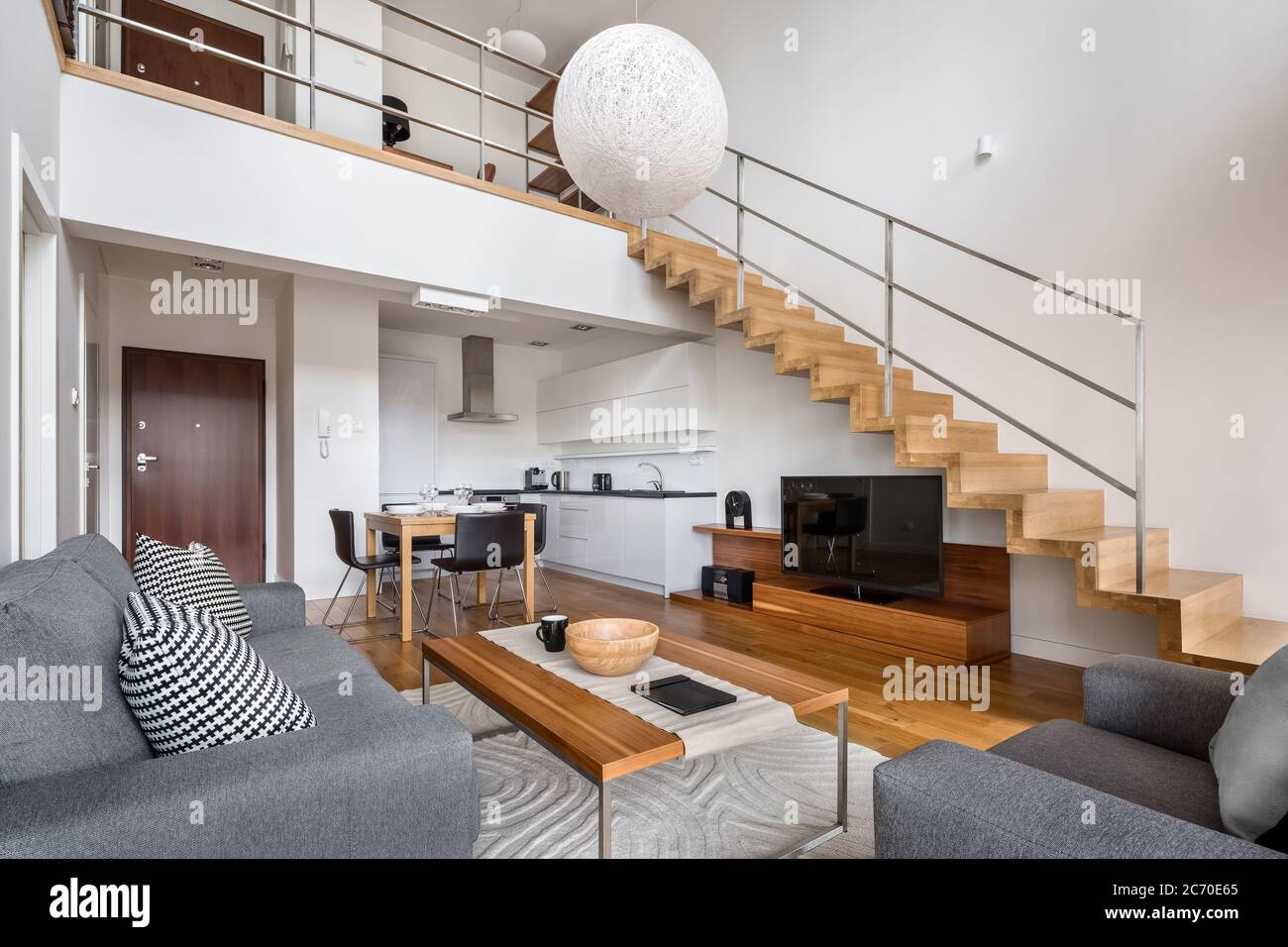 Moderne zweistöckige Wohnung mit Holztreppe und Wohnzimmer offen zur Küche Stockfoto