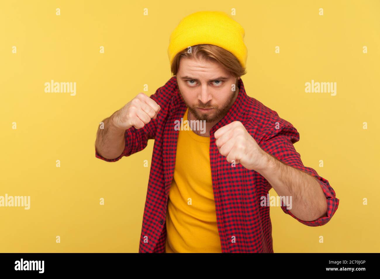 Aggressiver Hipster bärtiger Kerl in Beanie Hut, kariertes Shirt mit geballten Fäusten bereit zum Boxen, mit selbstbewussten Ausdruck zu schlagen, kämpfen Stockfoto