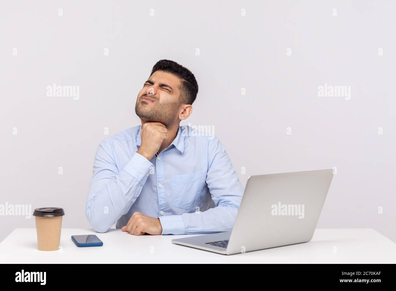 Ungesunde Grippe-kranke männliche Mitarbeiter sitzen Büroarbeitsplatz, berühren schmerzhaften Hals, leiden Halsschmerzen, entzündete Mandeln, schwer Schlucken. indoo Stockfoto