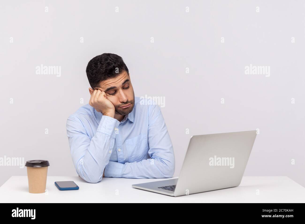 Verärgert faul ineffizient Mann Mitarbeiter sitzen Büro Arbeitsplatz, Blick auf Laptop-Bildschirm mit gleichgültigem Ausdruck, mit langwierigen Online-Gespräch Stockfoto