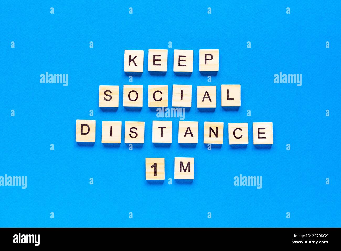 Wörter halten sozialen Abstand 1 m. Holzbeschriftung auf blauem Hintergrund. Information Zeichen der sozialen Abstand 1 m von Blöcken. Flache Anordnung Stockfoto