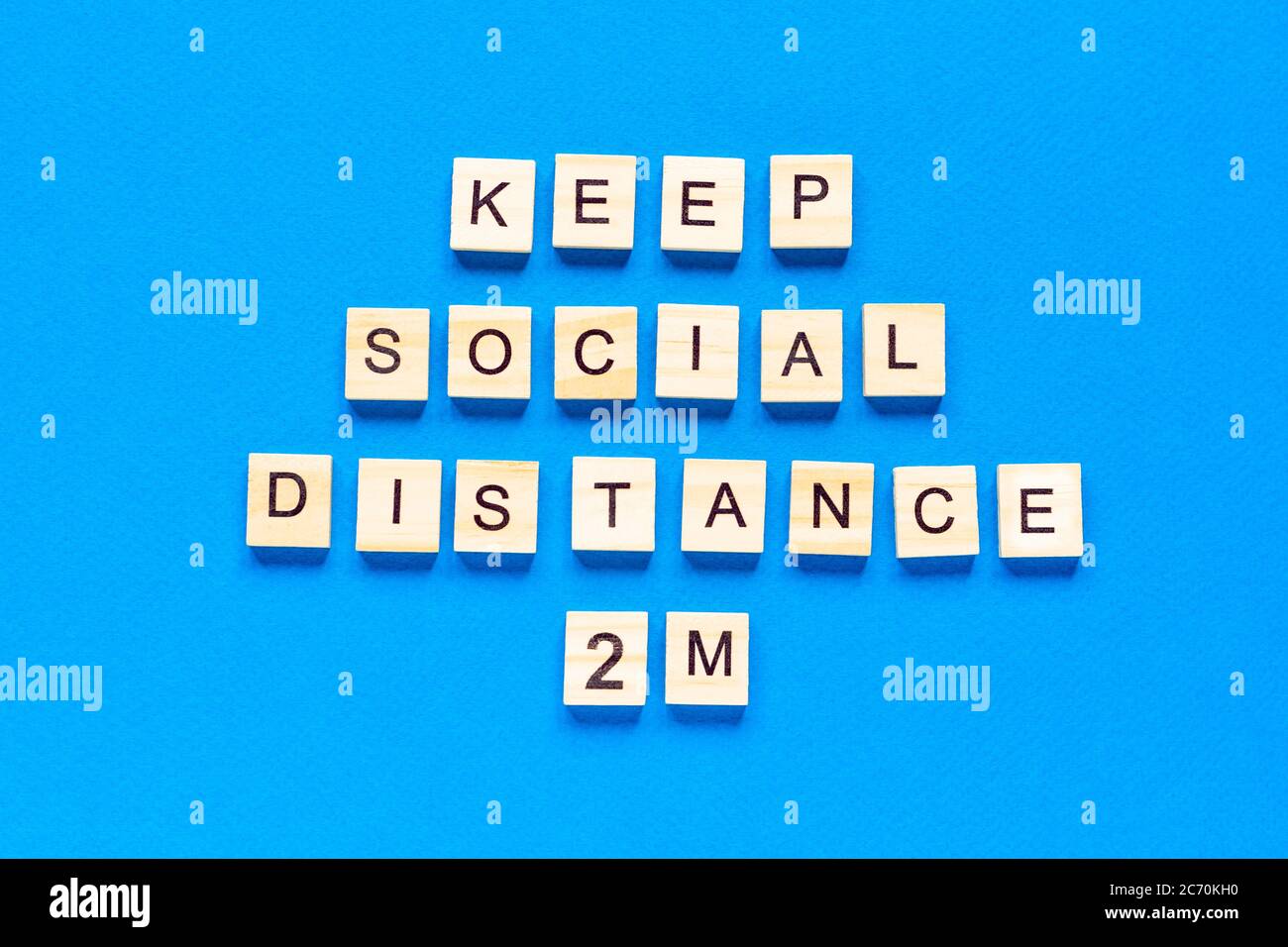 Wörter halten sozialen Abstand 2 m. Holzbeschriftung auf blauem Hintergrund. Information Zeichen der sozialen Abstand 2 m von Blöcken. Flache Anordnung Stockfoto