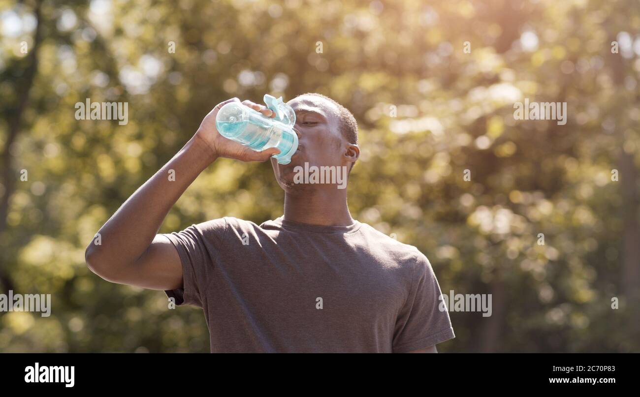 Schwarzer Mann, der Wasser trinkt, leidet unter heißem Wetter Stockfoto
