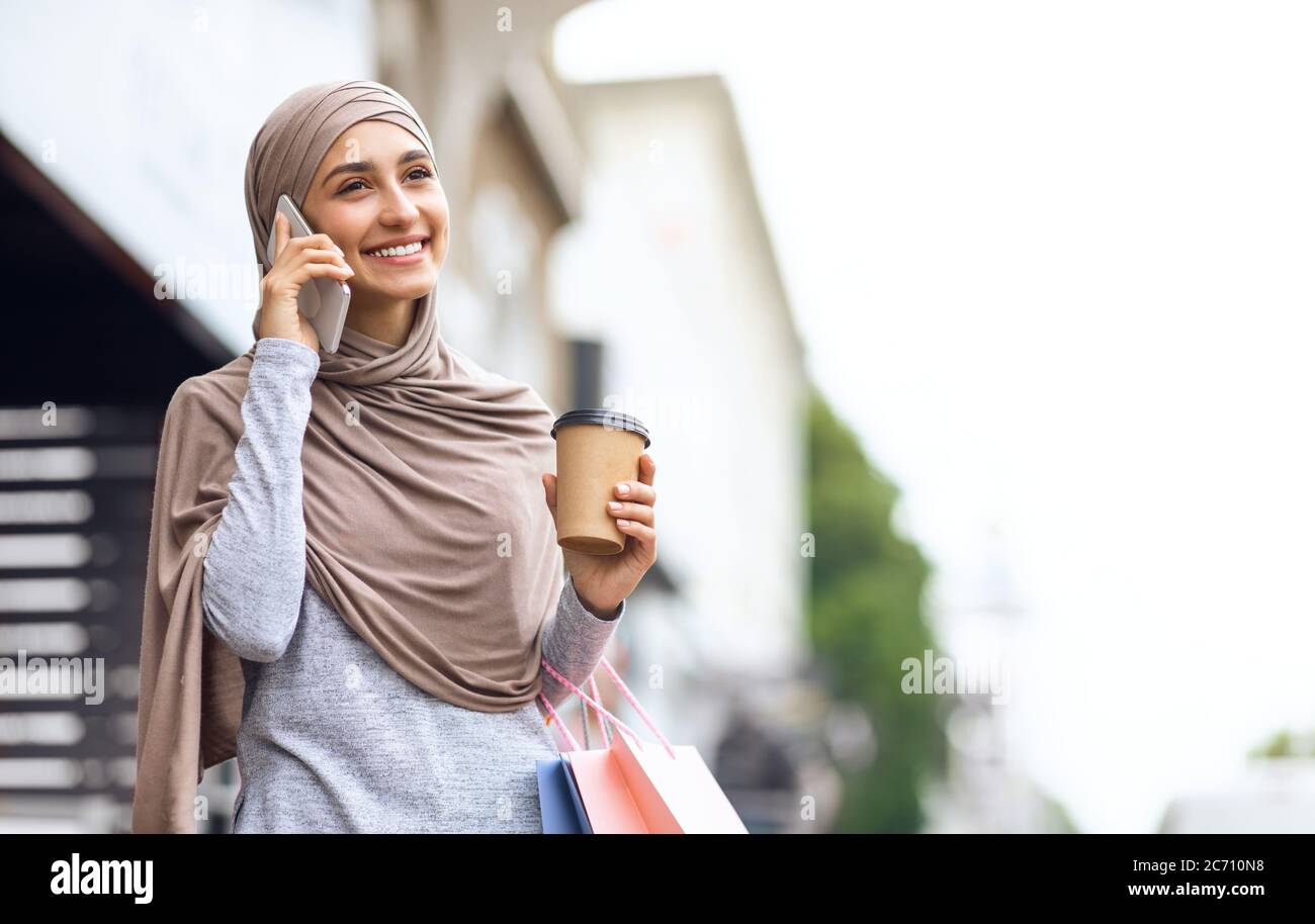 Fröhliche muslimische Frau mit Käufen auf dem Smartphone reden Stockfoto