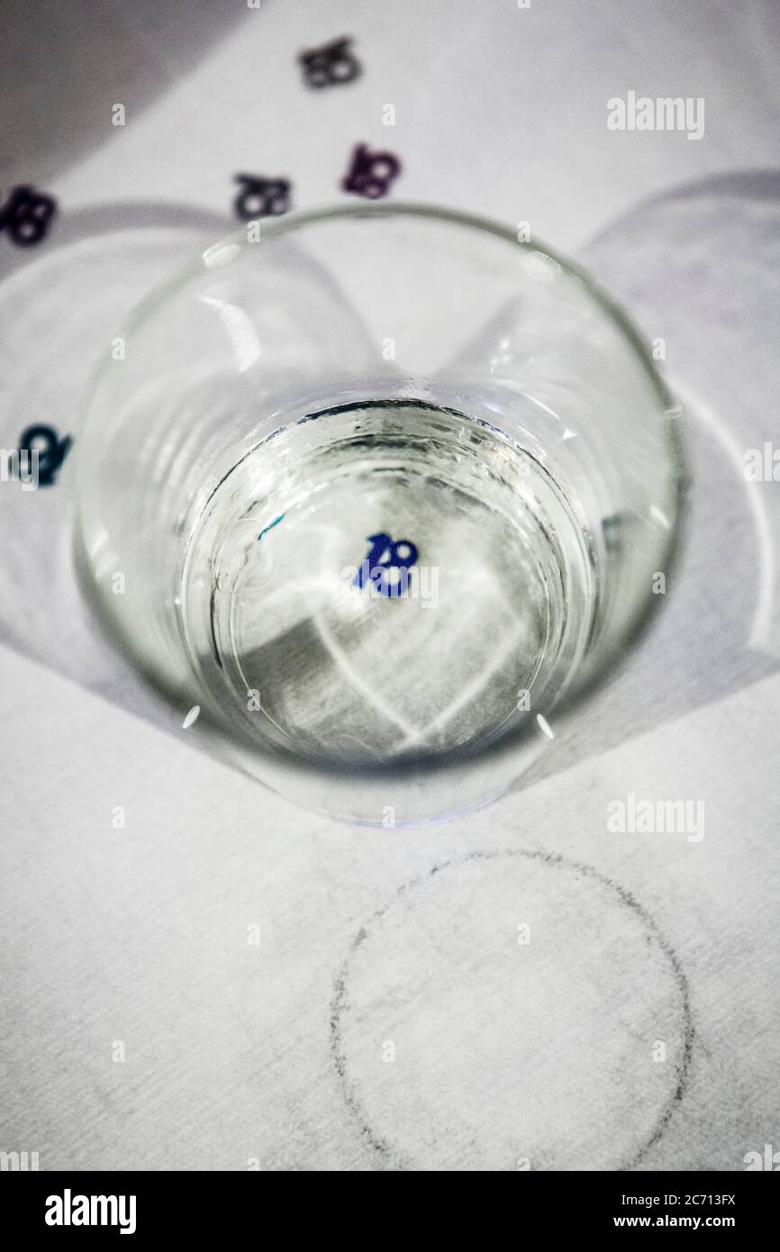 Halb leeres Glas mit der Nummer 18 darunter auf weißem Tischtuch Stockfoto
