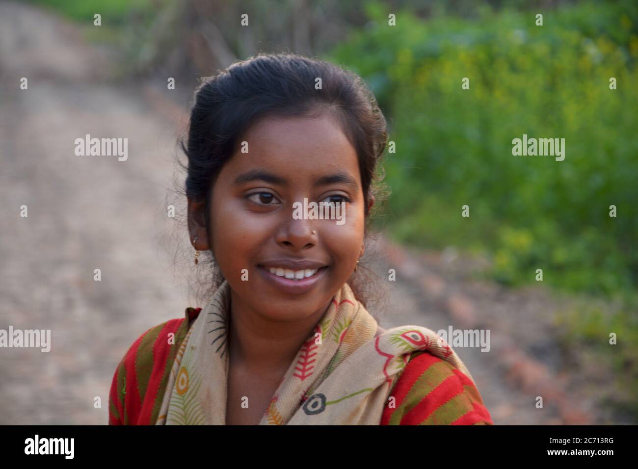 Ein indisches Teenager-Mädchen lächelt in einem ländlichen Dorf Feld, selektive Fokussierung Stockfoto