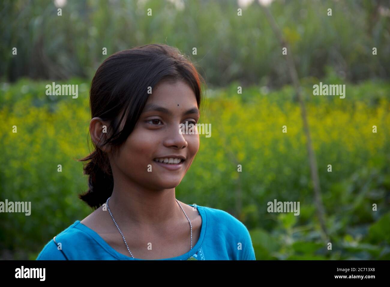 Ein indisches Teenager-Mädchen lächelt in einem ländlichen Dorf Feld, selektive Fokussierung Stockfoto