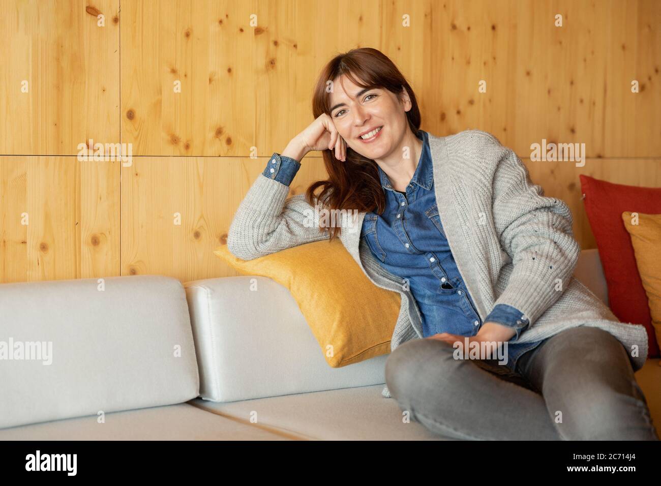 Schöne Frau sitzt und entspannt auf einem gemütlichen Platz Stockfoto