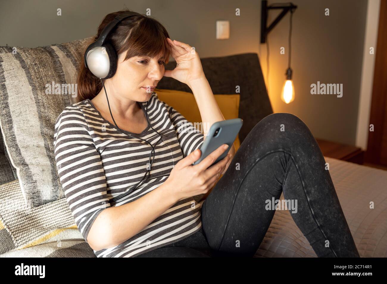 Frau am Telefon im Bett mit Symptomen einer Depression Stockfoto