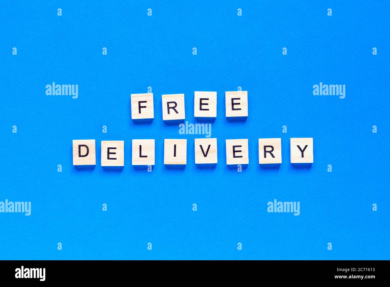 Kostenloser Versand Schriftzug in Holzbuchstaben auf blauem Hintergrund, Draufsicht. Servicekonzept, Lieferung, kontaktlose Lieferung, Promotion, kostenlos. Stockfoto