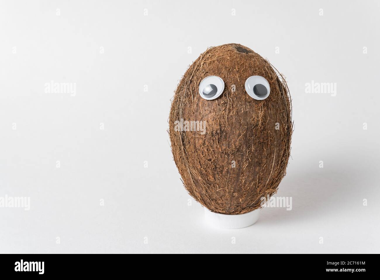 Braune Kokosnuss mit Schwanenaugen auf weißem Hintergrund. Nut Charakter mit lustigen Gesicht. Stockfoto