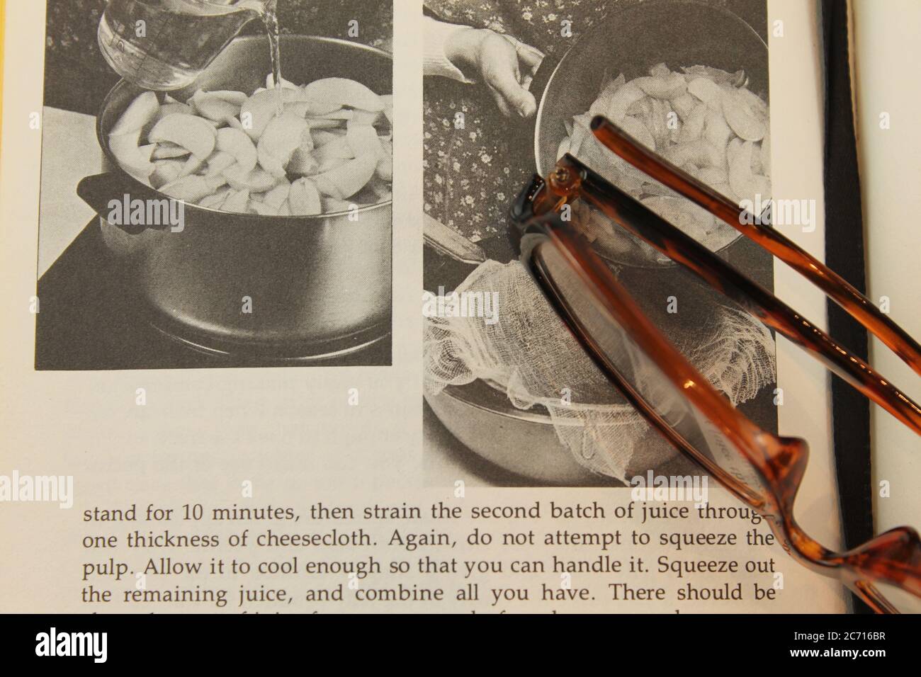 Offenes Buch mit Bildern von Obst mit einer braunen Brille auf der gegenüberliegenden Seite Stockfoto