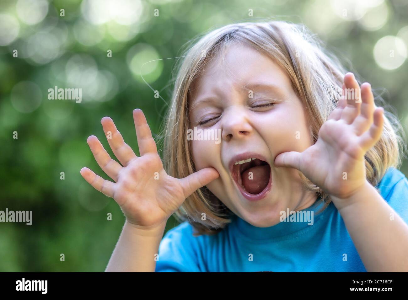 Portrait eines blonden Mädchens, das ein lustiges und lustiges Gesicht macht. Kindheit und Glück Konzept. Stockfoto