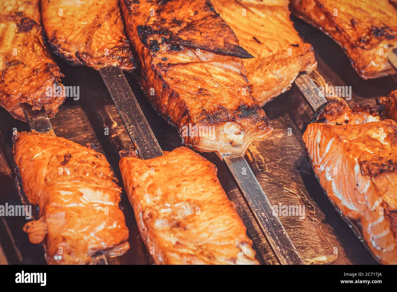 Nahaufnahme von saftig fetten frittierten Stücken von rotem Fisch auf Metallspieße mit geringer Schärfentiefe in einem Straßenmarkt. Street Food im touristischen Gebiet von ​​ Stockfoto