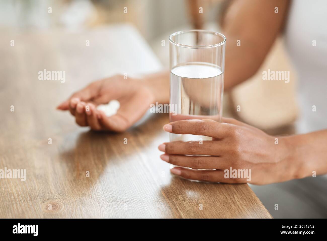 Unverkennbare schwarze Frau nimmt Medikamente mit Glas Wasser zu Hause Stockfoto