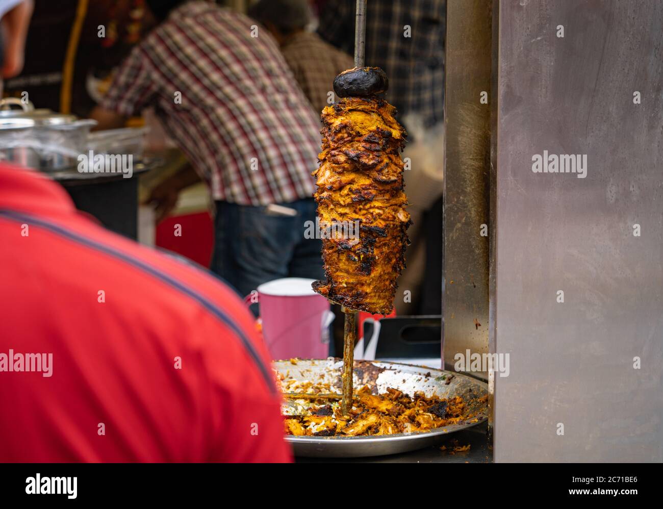 Huhn gegrillt in einem rotierenden Spieß auf einem Food Festival, um ein nahöstliches Essen namens Shawarma zu servieren Stockfoto
