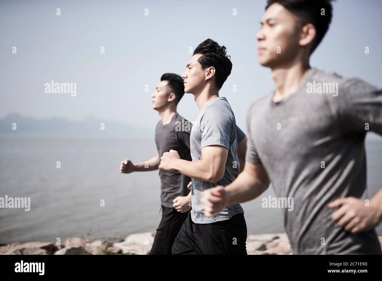 Drei junge asiatische Erwachsene Männer laufen Joggen im Freien am Meer Stockfoto