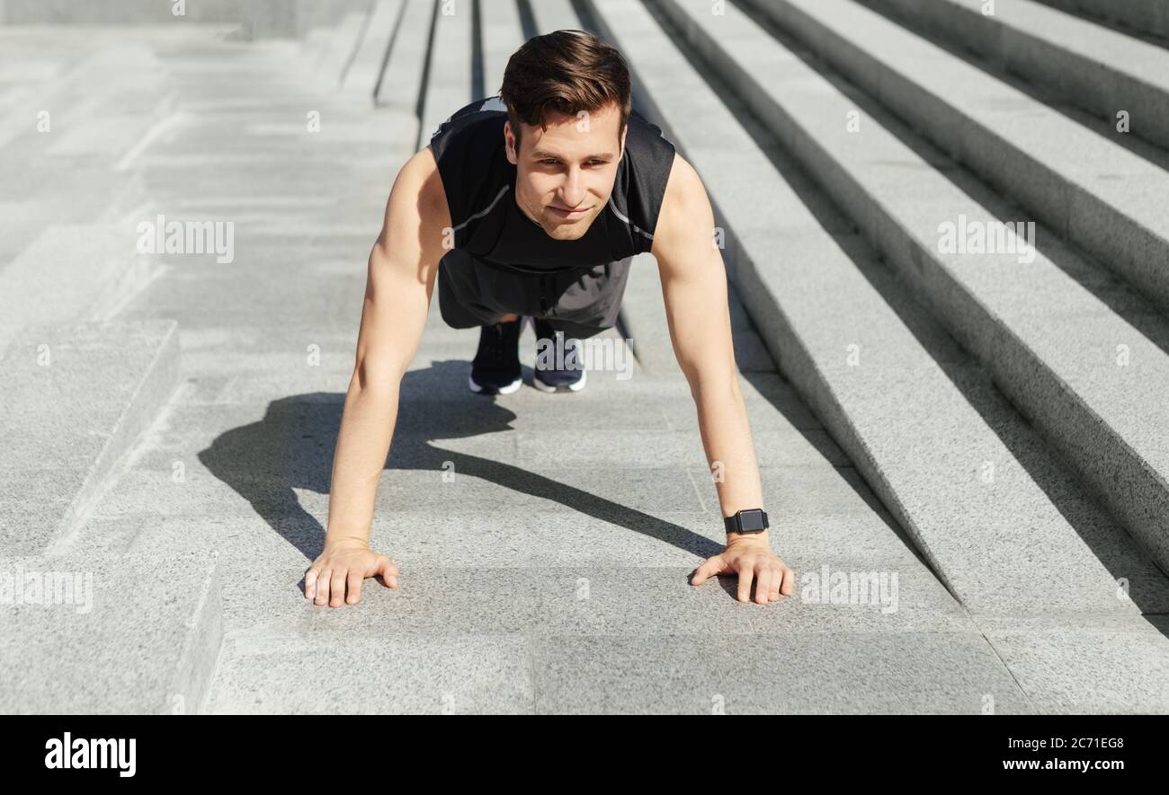 Outdoor-Sport. Mann in Sportbekleidung mit smarter Uhr, Liegestütze an der Treppe Stockfoto