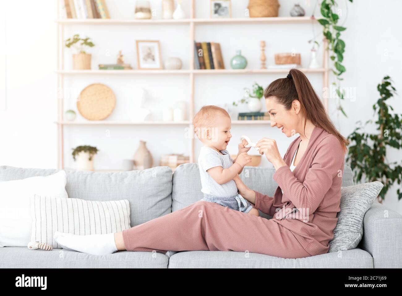 Glück Der Mutterschaft. Happy Baby spielt mit Mutter auf der Couch zu Hause Stockfoto