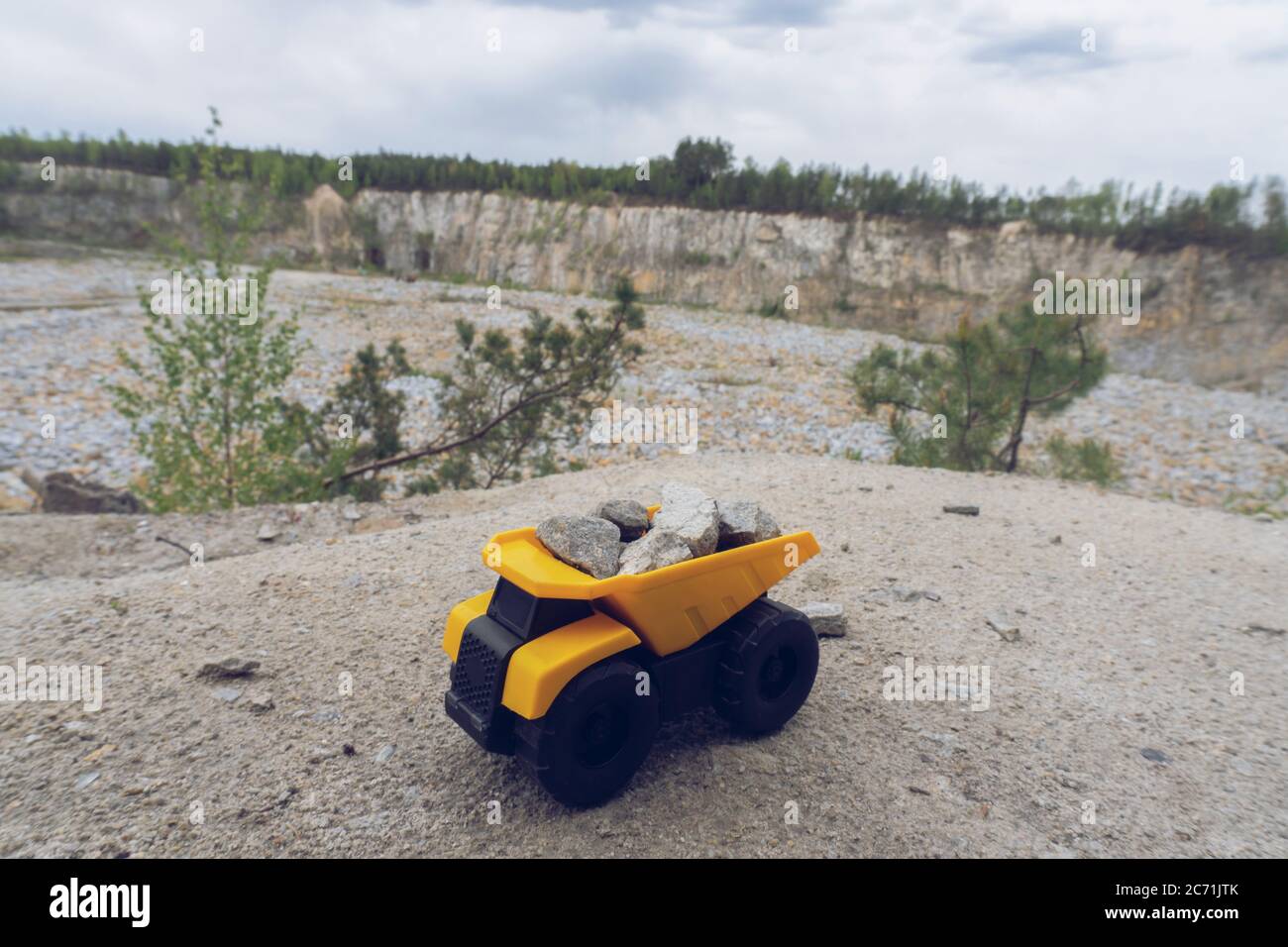 Kleines gelbes Auto Spielzeug, Bergbau LKW mit Steinen auf dem Hügel im Hintergrund des Steinbruchs, Stockfoto