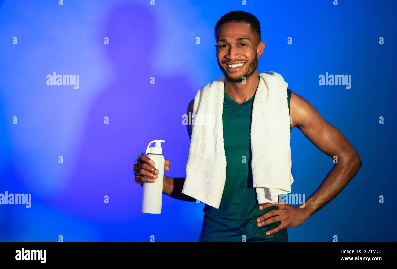 African Fitness Guy Holding Flasche Wasser Stehen Im Studio Stockfoto