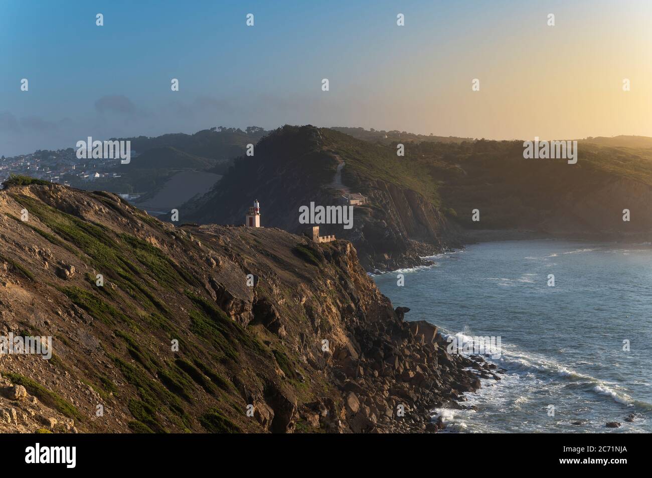 Blick auf die Landzungen am Eingang der Bucht São Martinho do Porto, mit dem Leuchtturm, bei Sonnenuntergang. Stockfoto
