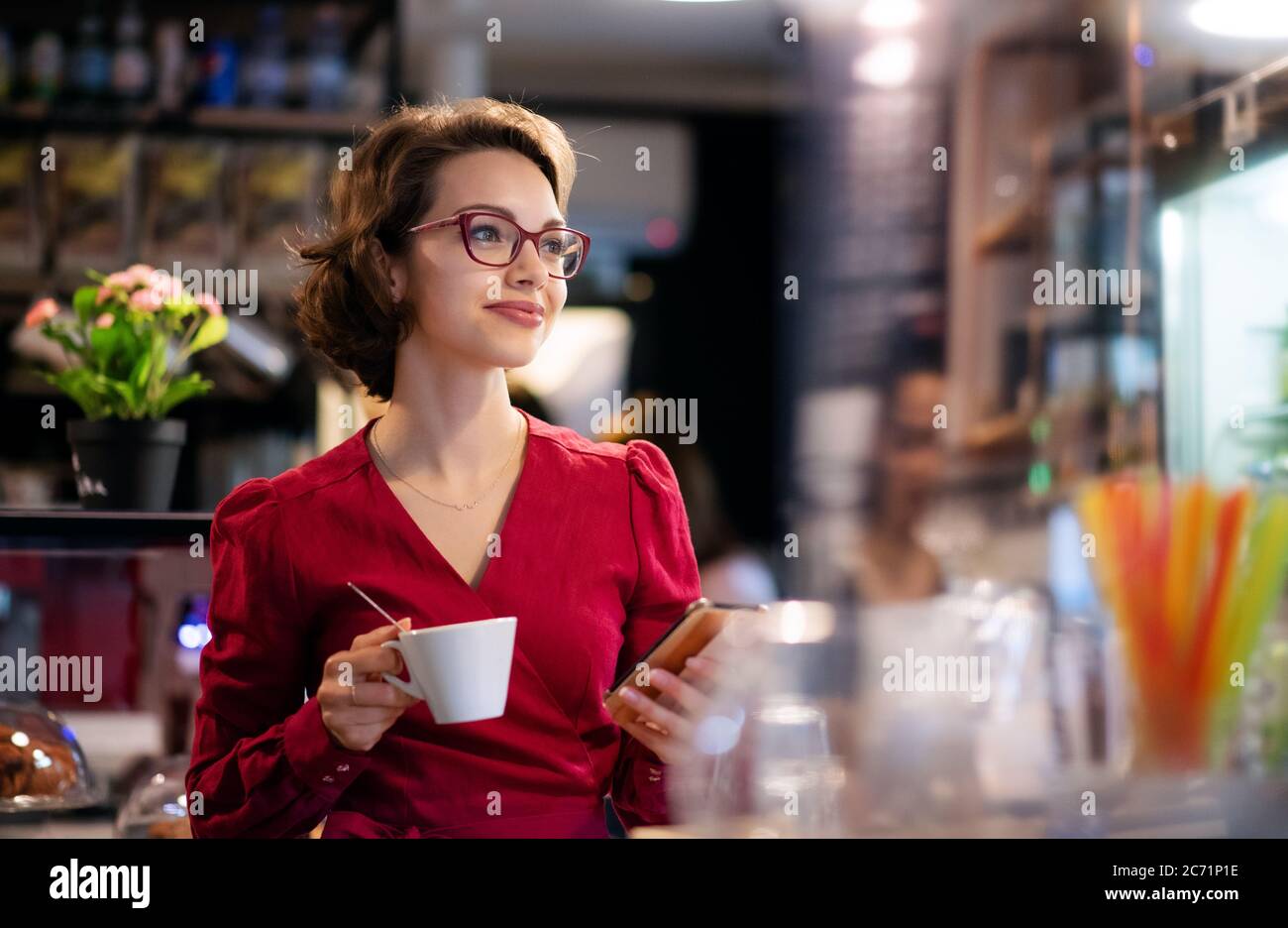 Junge Frau mit Kaffee im Café, mit Smartphone. Stockfoto