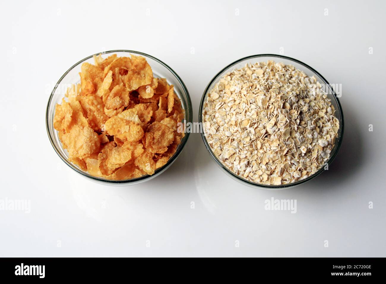 Schüssel voll mit Hafer und Cornflakes. Haferbrei Hafer in Müslischale und Cornflakes auf weißem Hintergrund. Gesunde Ernährung Konzept-Haferflocken und Cornflakes Stockfoto