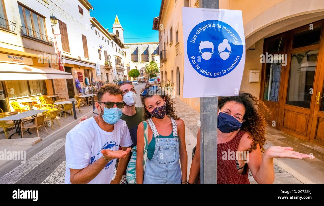 Junge Spanier bedauern und akzeptieren die kommende Generalmaskenpflicht in Spanien. Im Ferienort Santayi gibt es ein Schild, das darauf hinweist, dass Masken CO sind Stockfoto