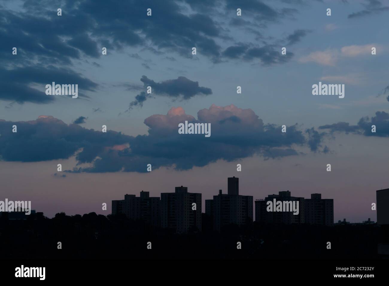 Ein blauer, wolkiger Himmel in der Abenddämmerung mit warmen orange und violetten Untertönen über der Bronx Skyline Stockfoto