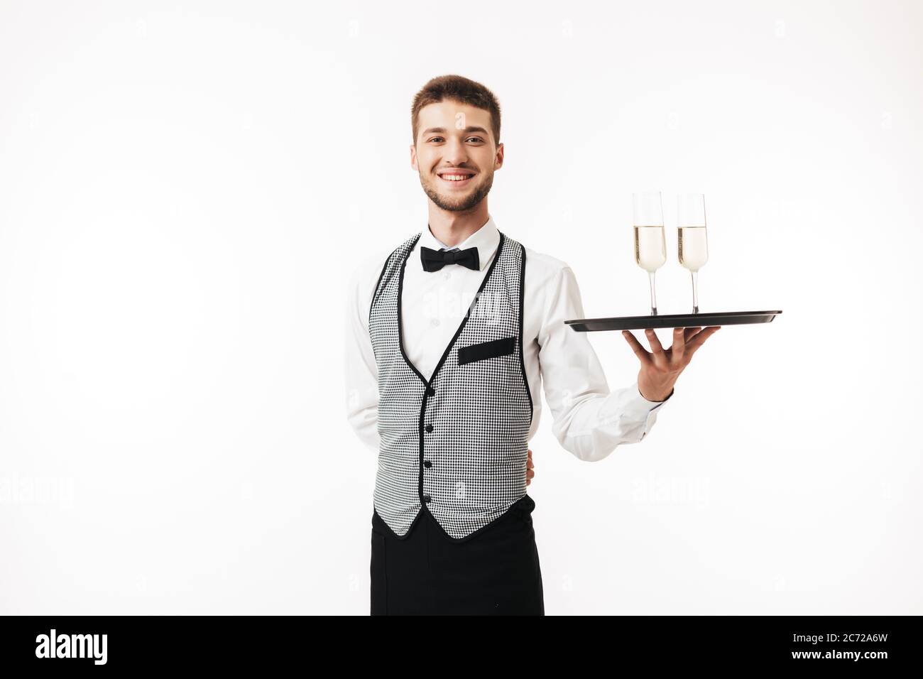 Fröhlicher Kellner in Uniform, der fröhlich in der Kamera mit einer Brille auf weißem Hintergrund schaut Stockfoto