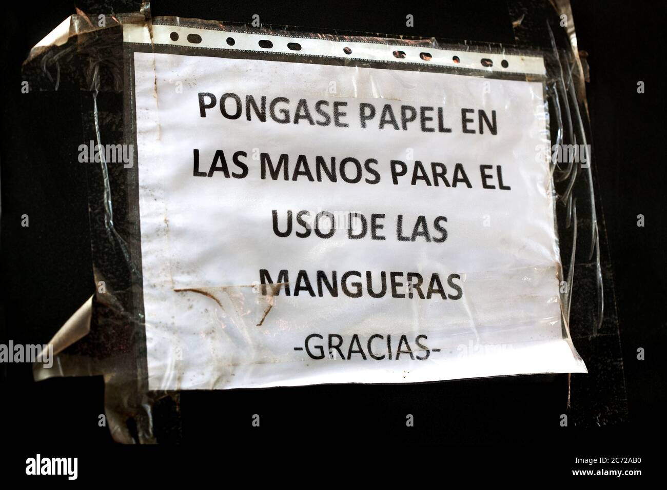 Hinweis an der Tankstelle, die Kunden auffordert, ihre Hände vor dem Umgang mit der Zapfpistole mit Papier zu schützen, Caspe, Spanien. Stockfoto