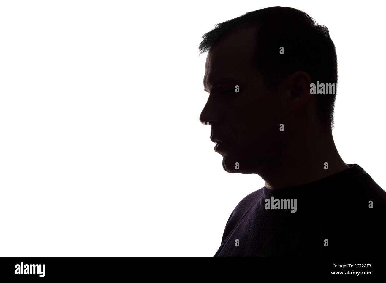 Porträt eines jungen Mannes, unrasiert, Seitenansicht - dunkel isoliert Silhouette Stockfoto